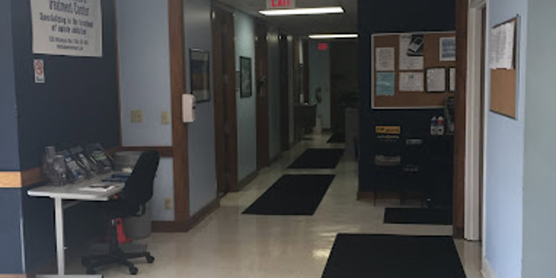 A clean and well-lit hallway inside the Charlotte Treatment Center, featuring light blue walls, seating, and an information desk near the entrance.