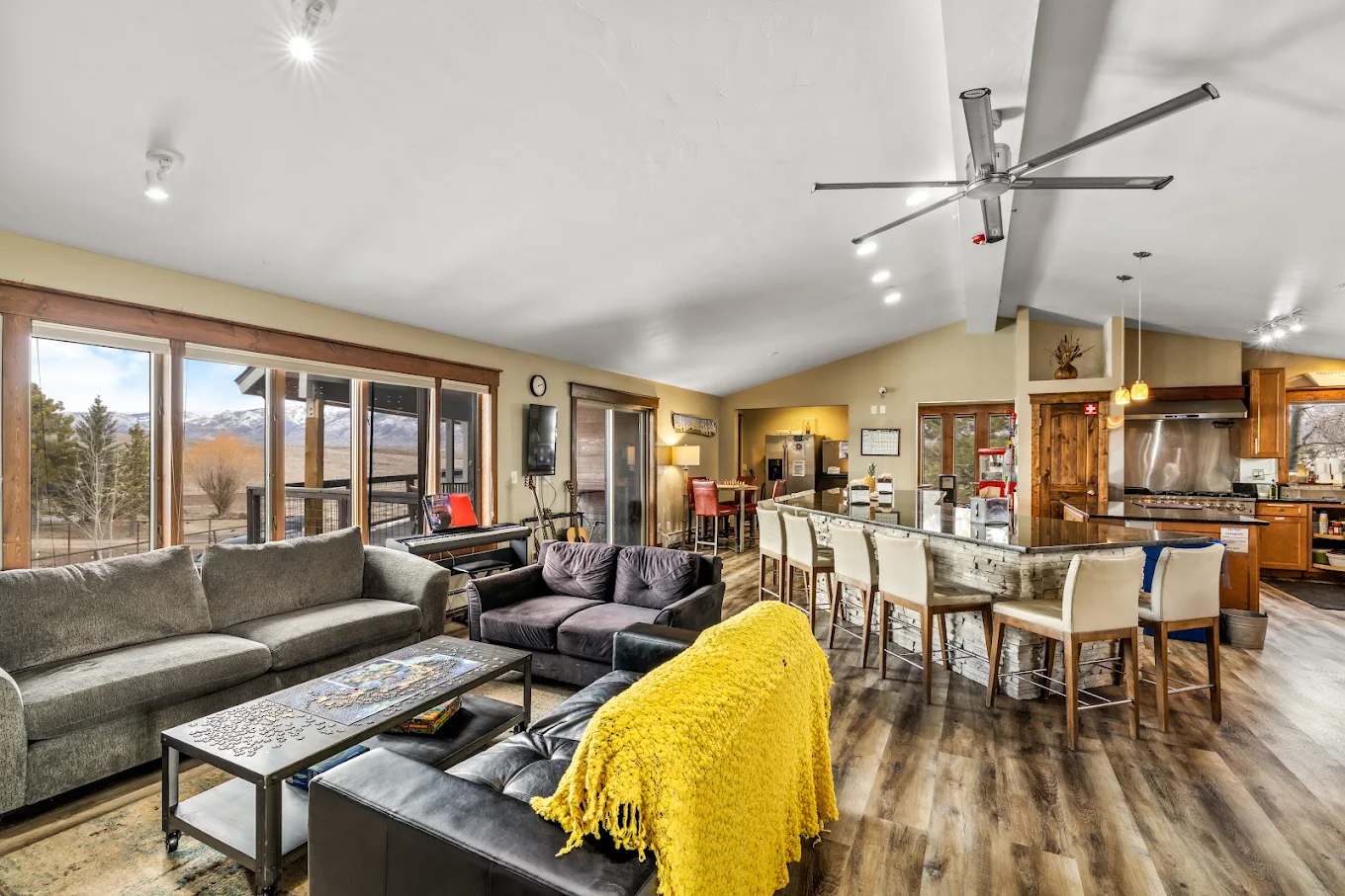 Spacious open-concept living area with sofas, kitchen seating, large windows, and mountain views at Foundry Treatment Center