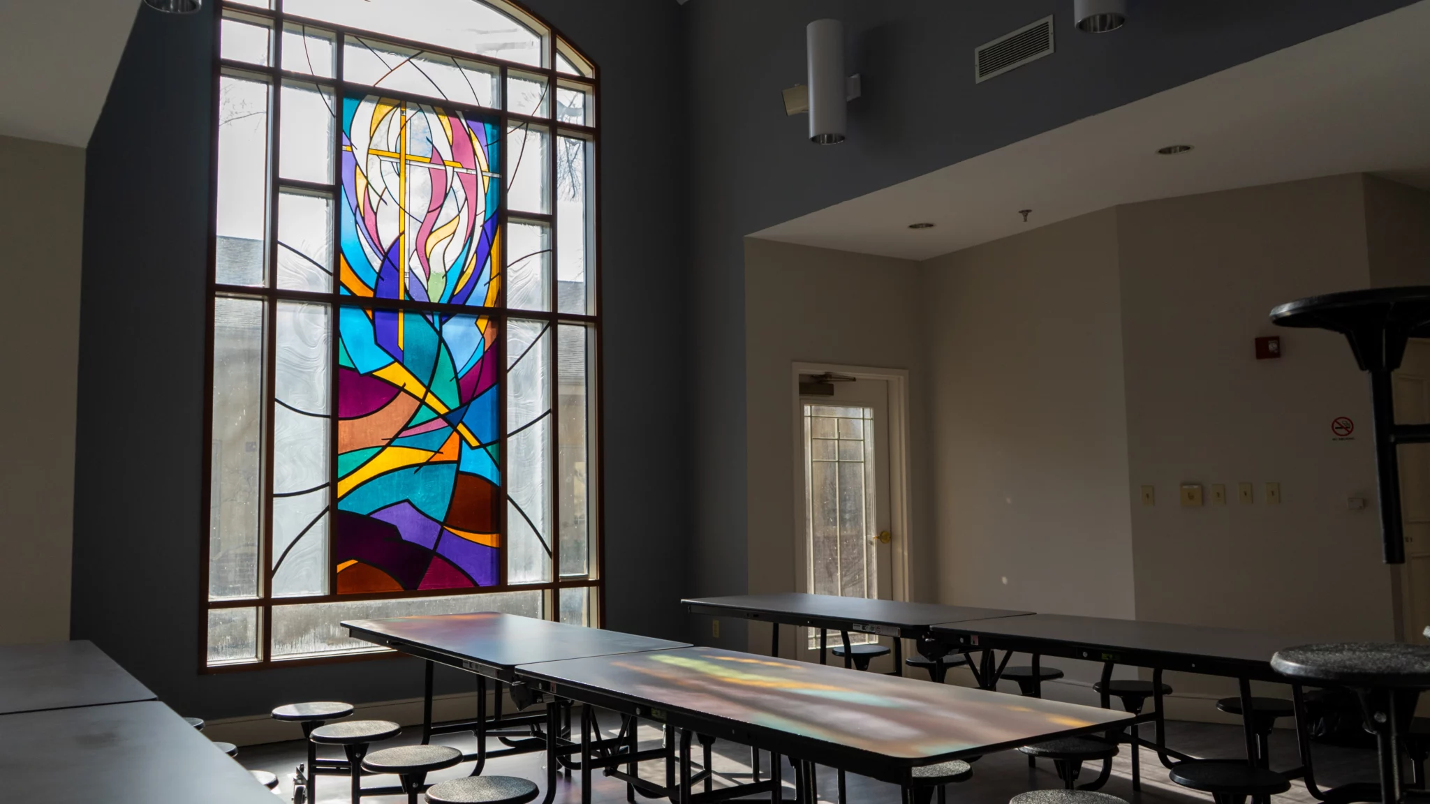 Dining area with tables beside large stained glass window