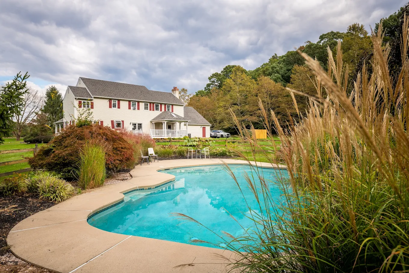 Backyard pool surrounded by trees and lounge chairs