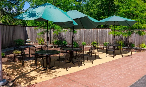 Patio with tables and green umbrellas surrounded by trees