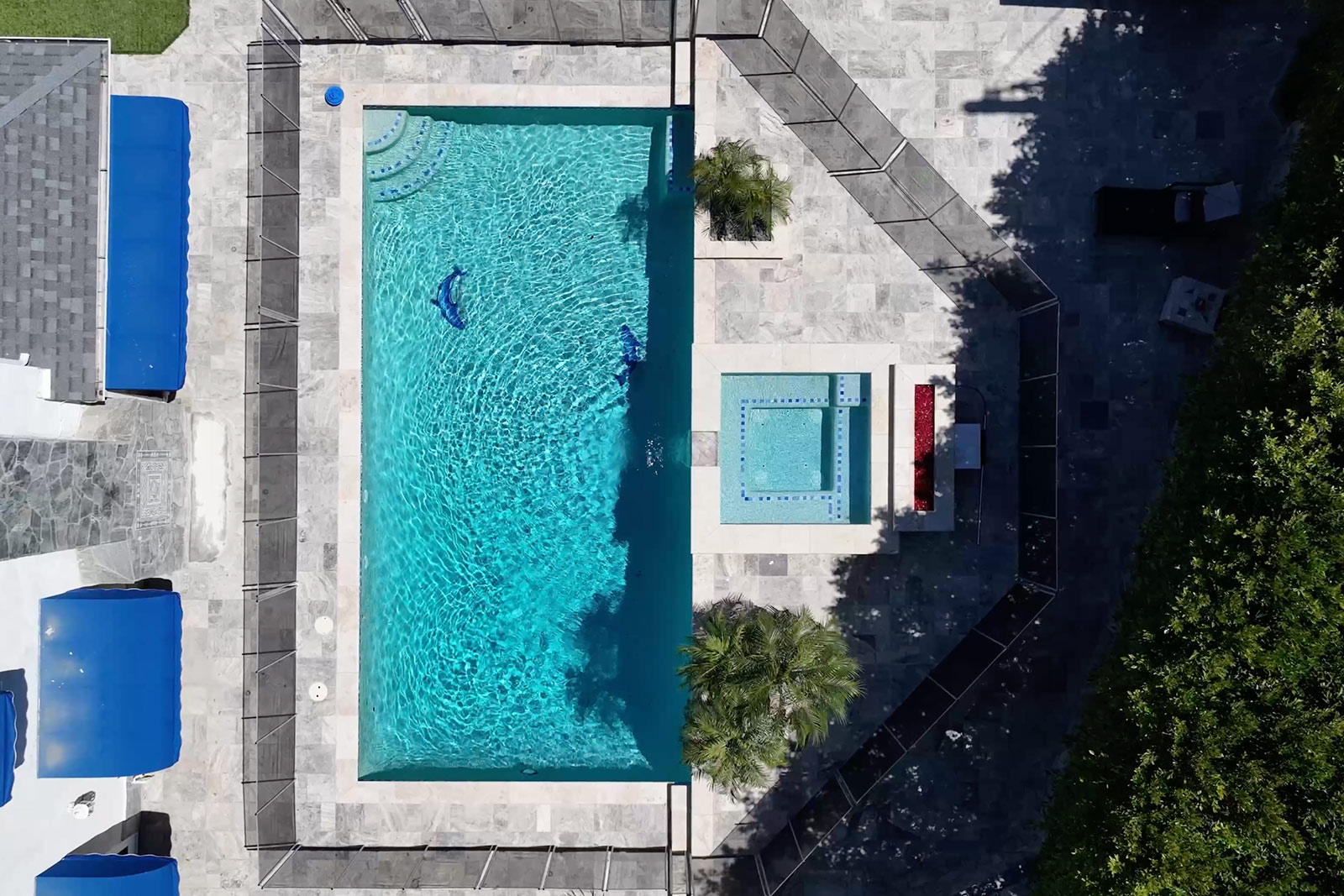 Aerial view of a fenced pool and hot tub surrounded by greenery.