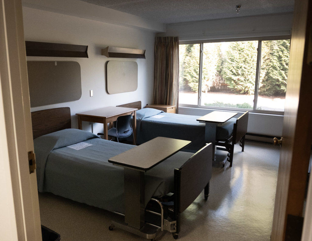 Shared rehab bedroom with two beds and large window
