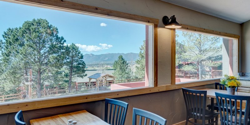 Bright dining area with large windows showcasing beautiful mountain and forest views, offering a peaceful setting for meals and conversation.