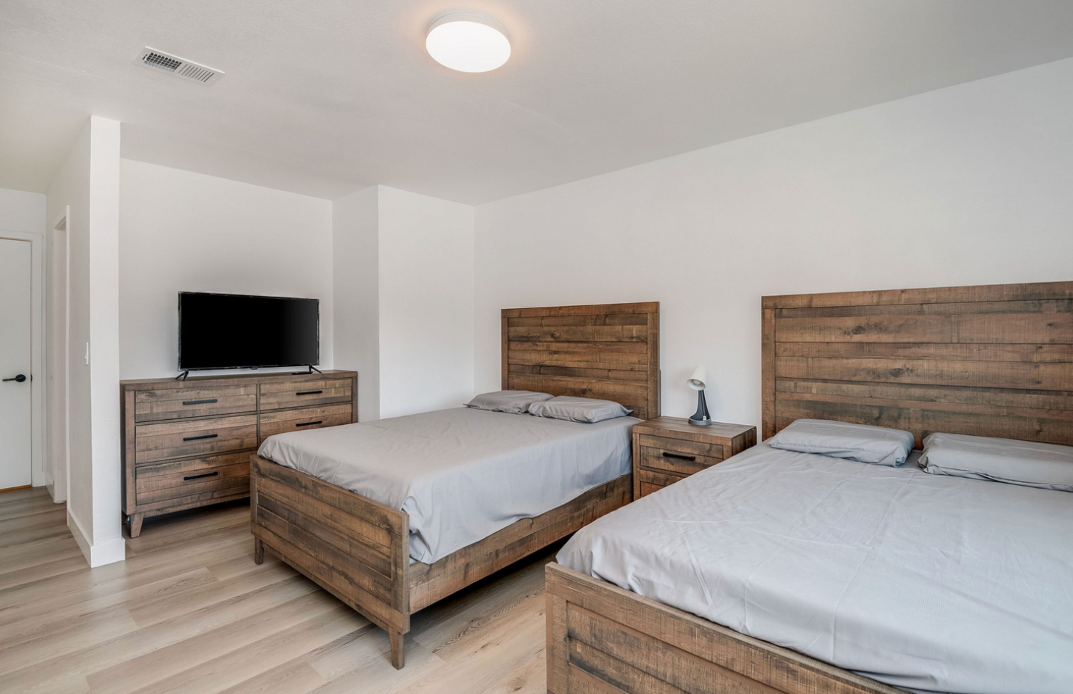 Bedroom with two wooden beds and a TV on a dresser.