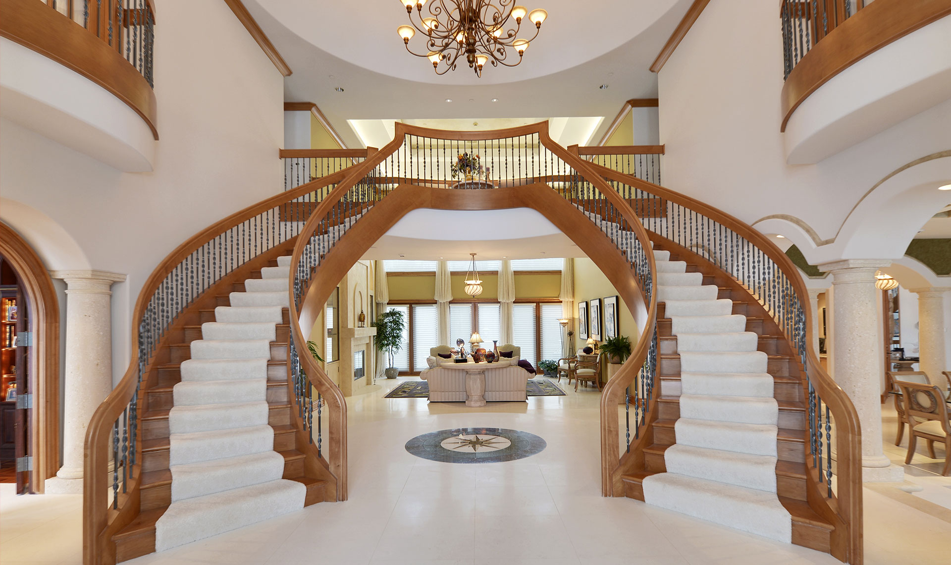 Grand double staircase in bright, elegant luxury foyer interior.