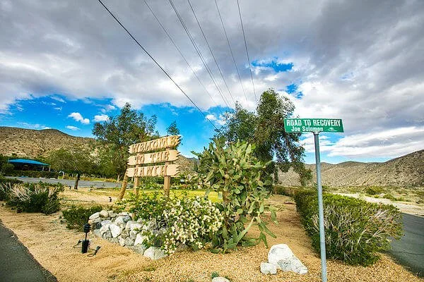 Entrance sign surrounded by desert plants and mountain scenery