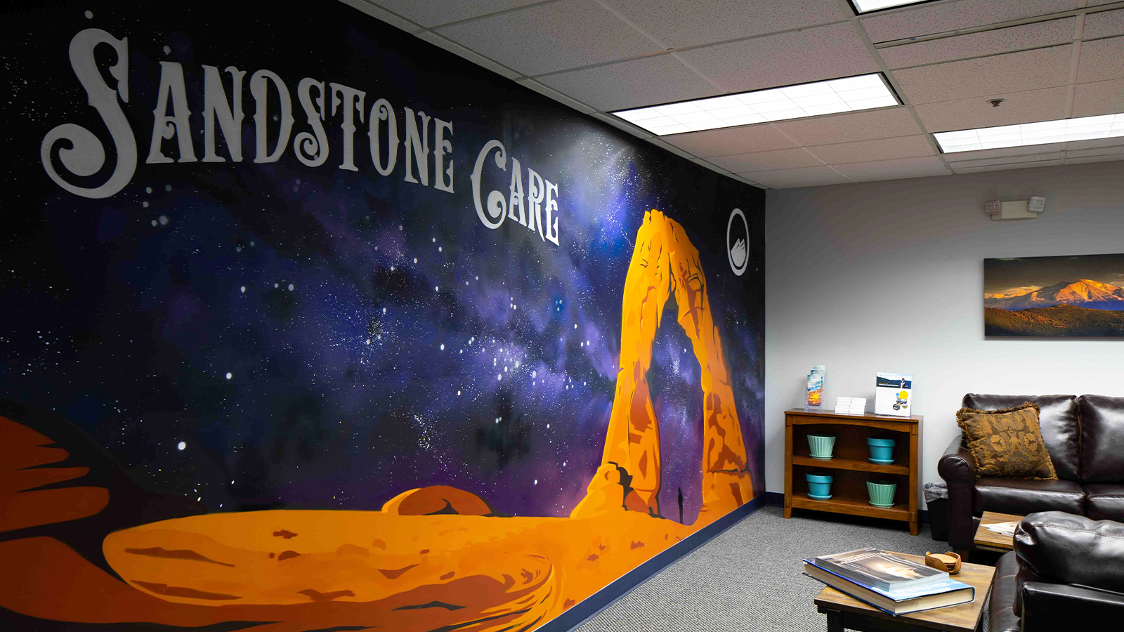 A waiting area with a mural reading "Sandstone Care" and a leather couch.