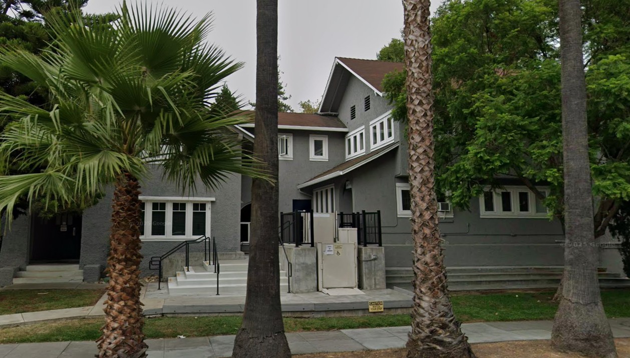 Gray residential rehab building with palm trees and entry ramp