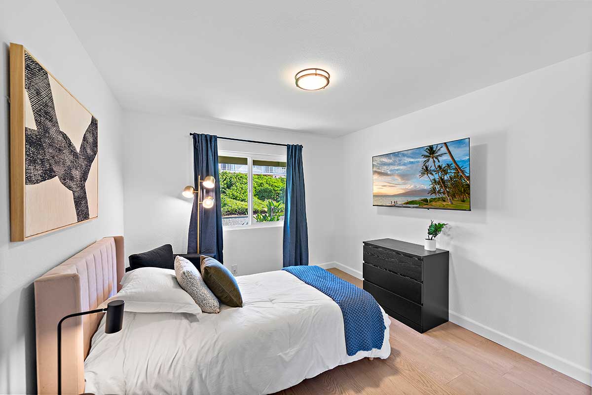 Bright bedroom with bed, dresser, TV, and garden view