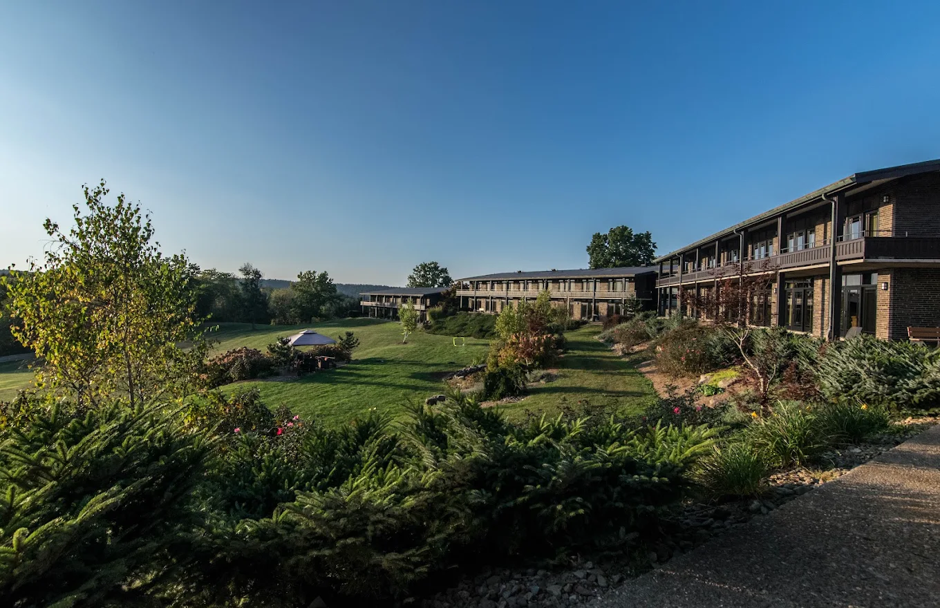 Landscaped hillside and lodge-style buildings under blue sky