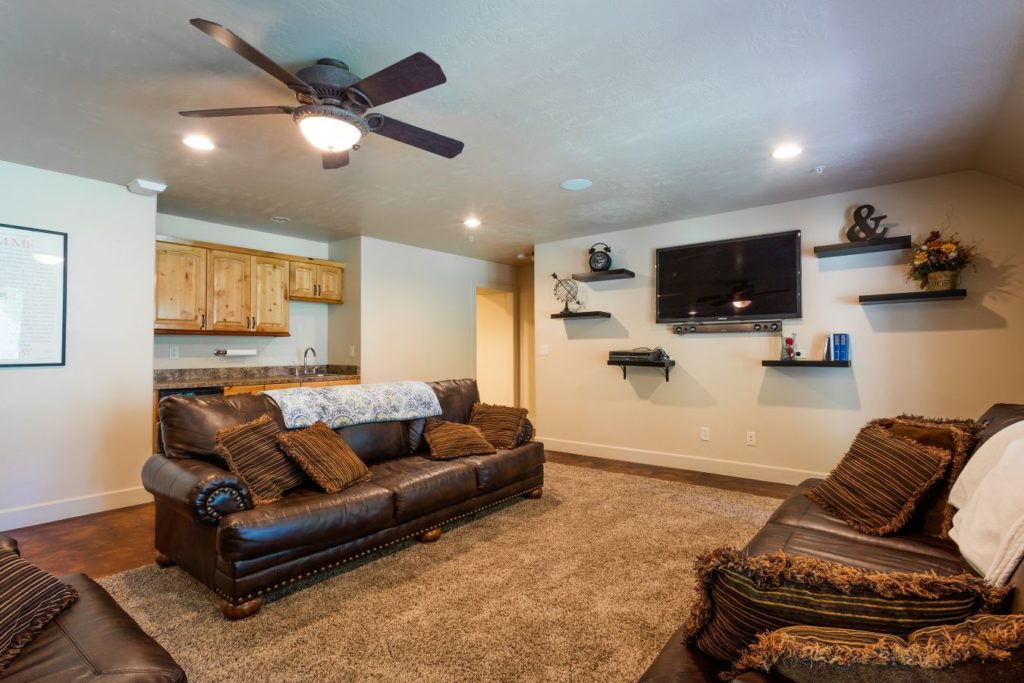 TV lounge with leather couches and wall-mounted television.