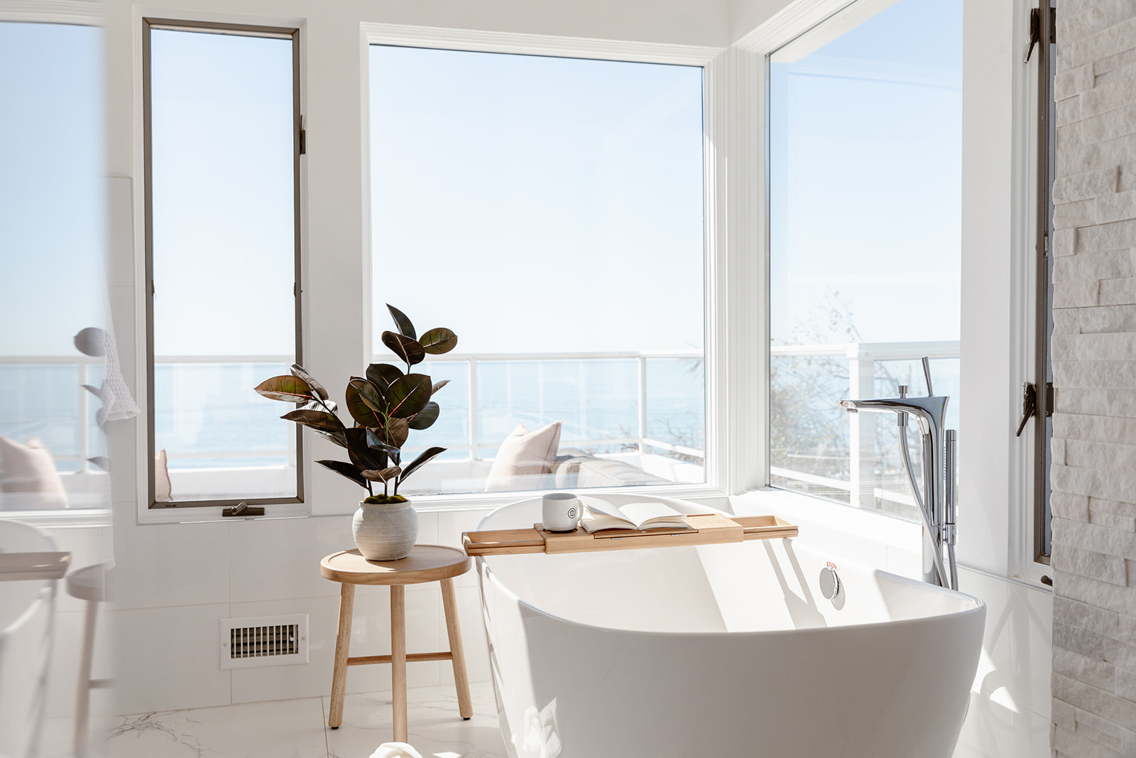 Bright bathroom with a freestanding tub and ocean views.