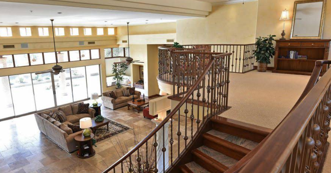 Open lounge with couches, large windows, and curved staircase