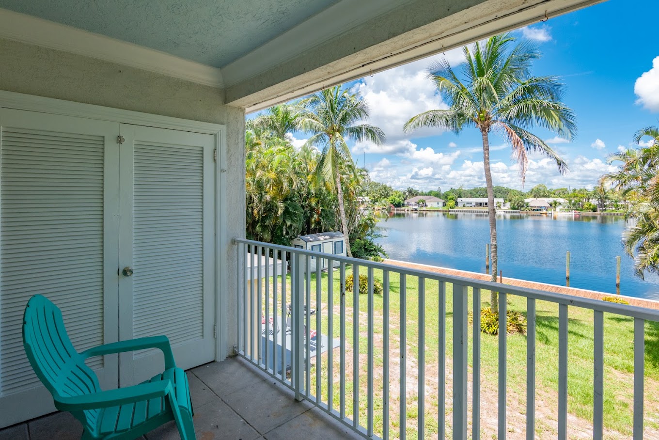 Balcony with chairs and lake view framed by palm trees
