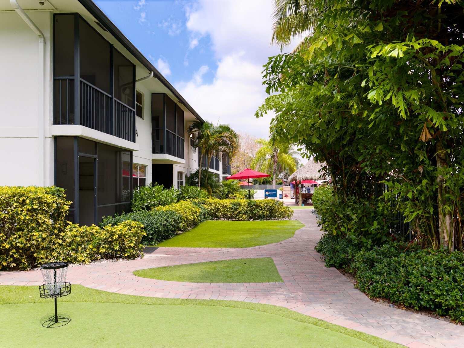 Garden walkway beside residential buildings with shaded seating.