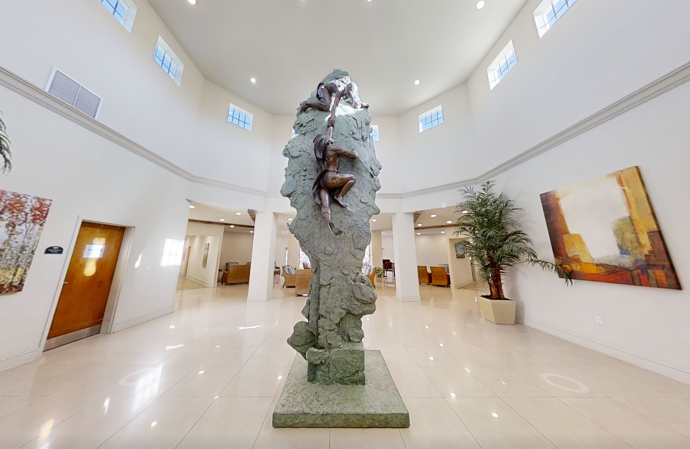 Bright lobby with tall climbing statue and polished floors