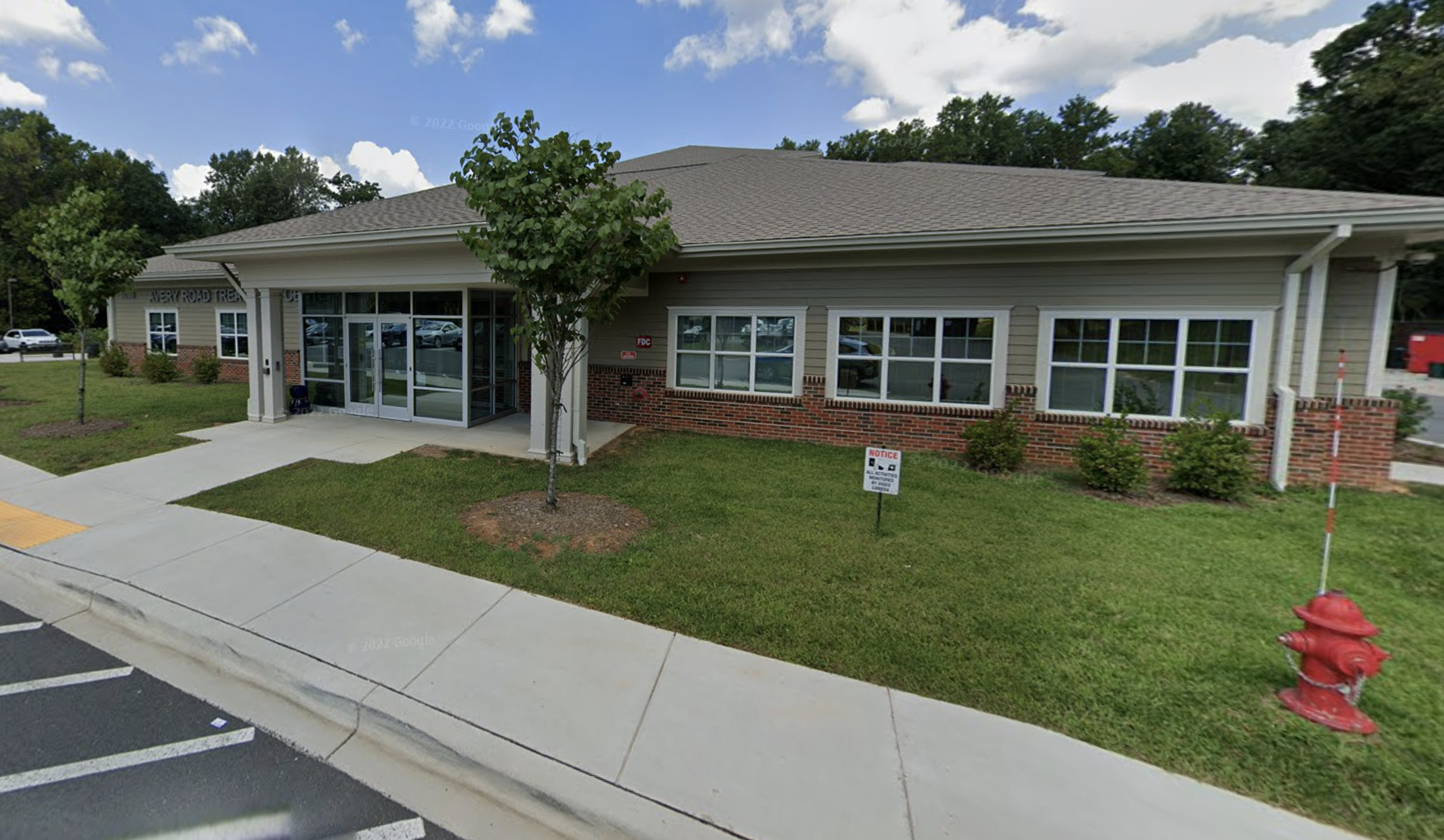 Single-story brick building with landscaped lawn and sidewalk