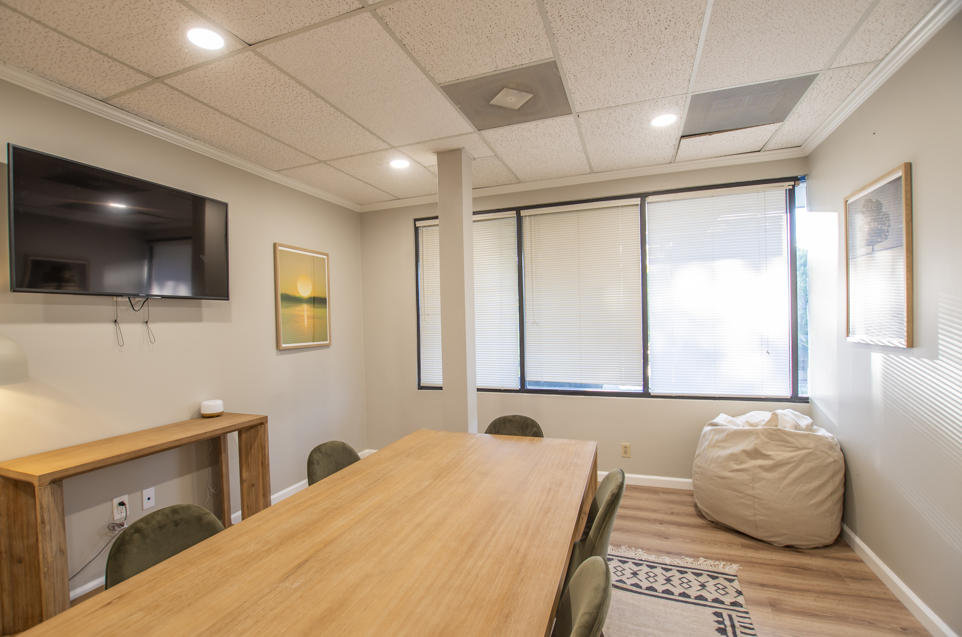 Meeting room with wood table, TV, and natural lighting