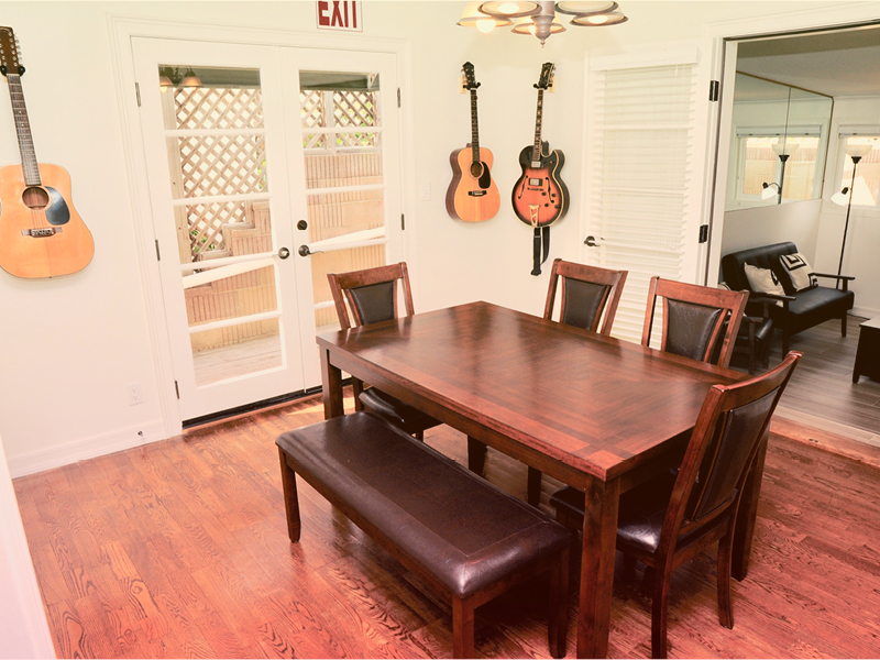 Dining area with a wooden table and guitars on the wall.