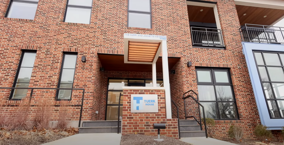 Brick building entrance with Tuerk House sign and awning