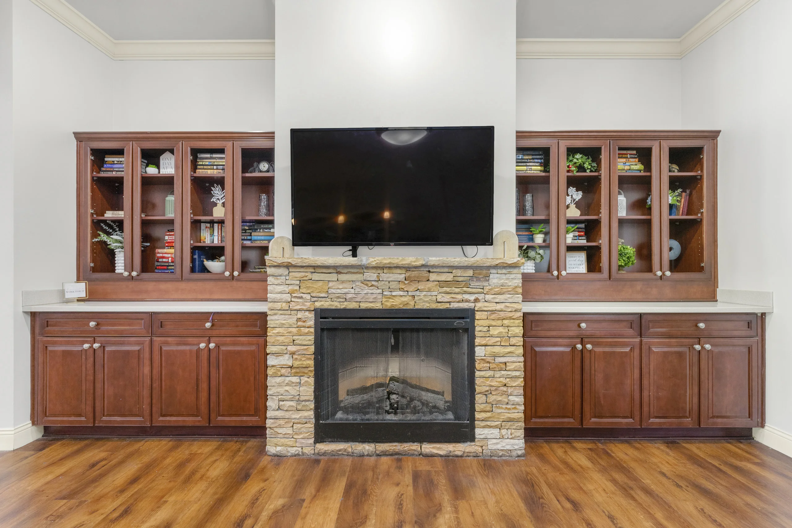 Cozy library with built-in bookshelves, stone fireplace, and television for reading and relaxation