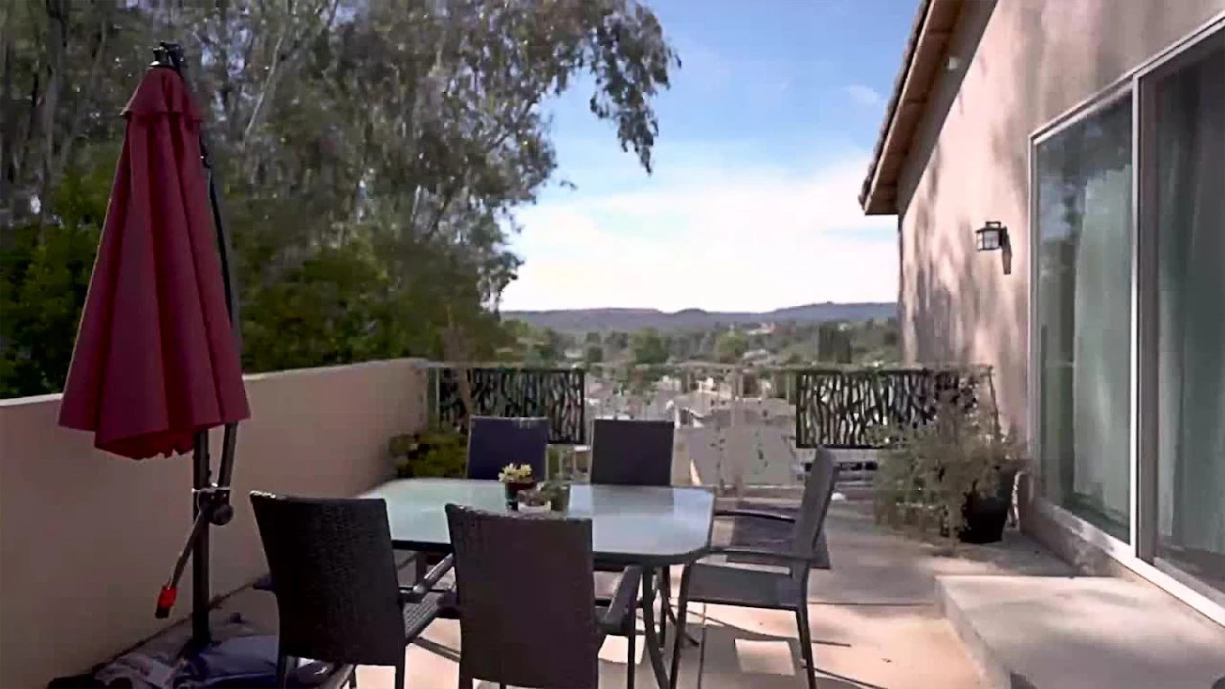 Patio with table, chairs, and umbrella overlooking hills