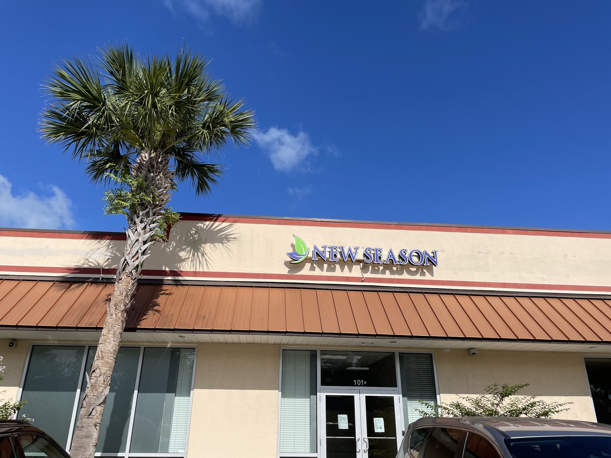 New Season sign above entrance with palm tree and clear sky
