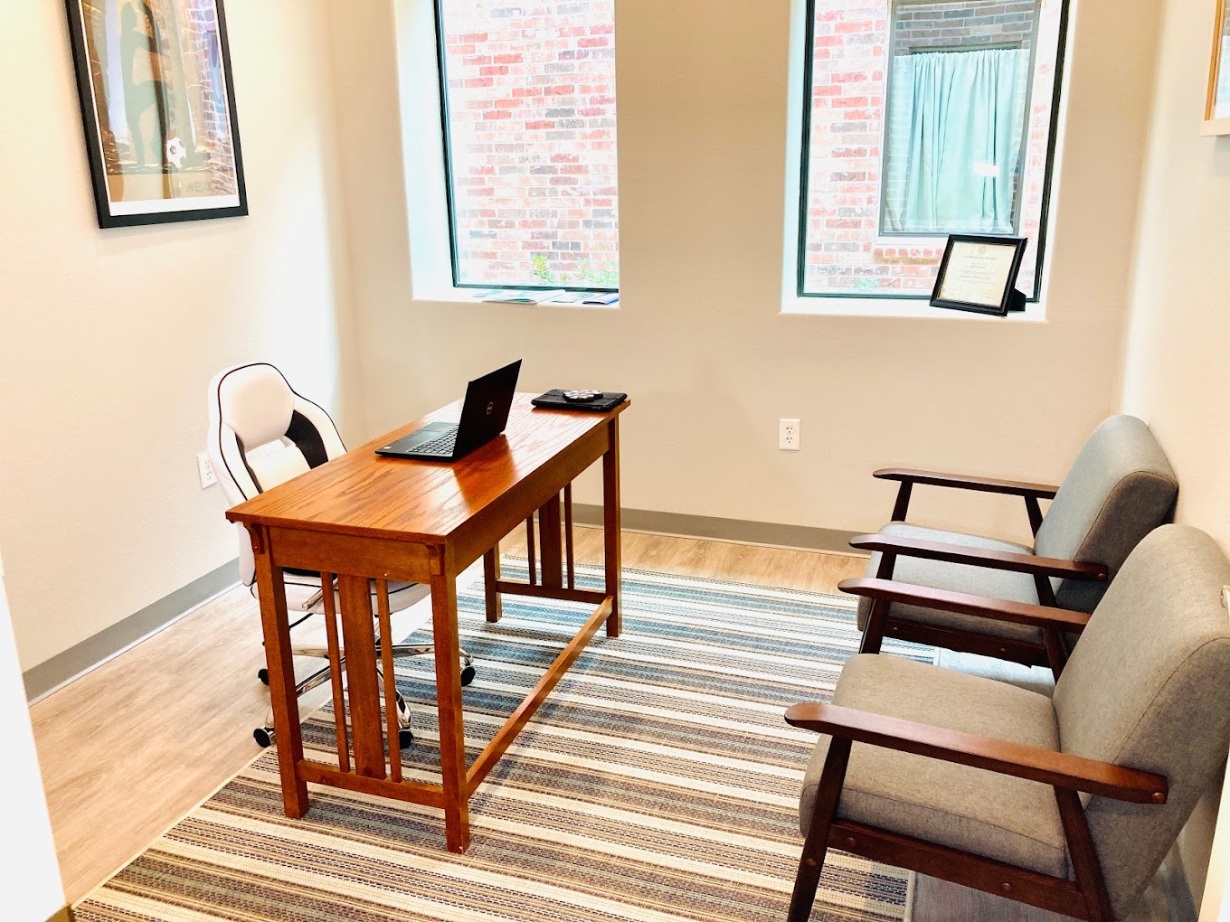 A private counseling office with a wooden desk, chairs, and natural lighting.