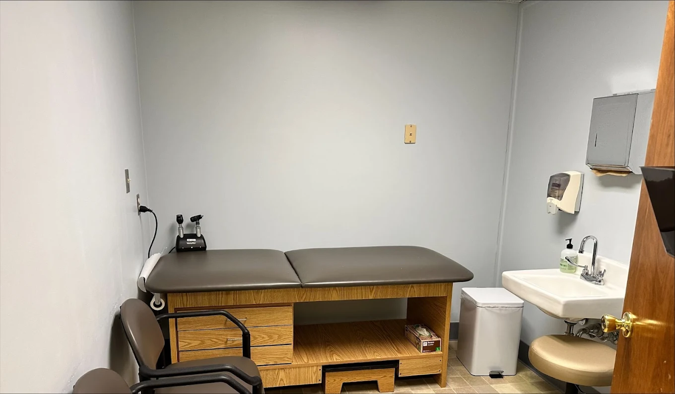 Medical exam room with examination table, sink, and patient seating