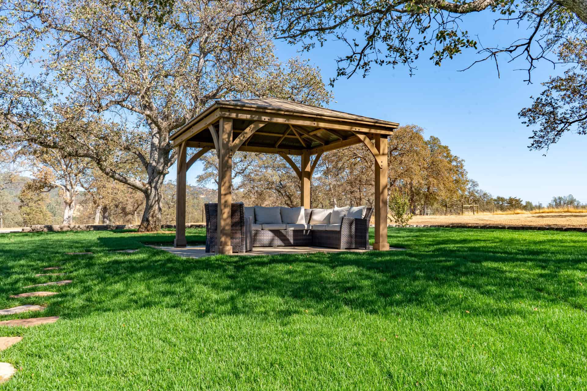 Covered outdoor seating area surrounded by trees and grass