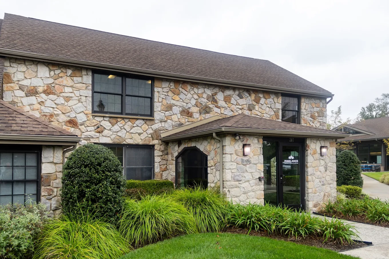 Stone facility building with landscaped entrance and shrubs