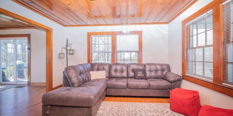 Living room with a gray sectional couch and wooden ceiling.