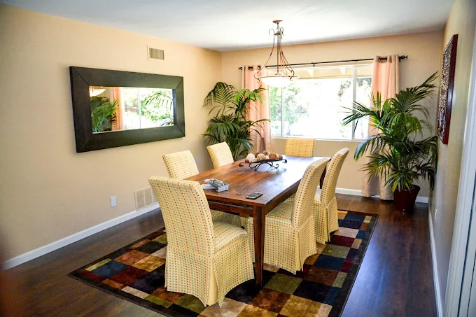 Dining room with wooden table, six chairs, and large mirror