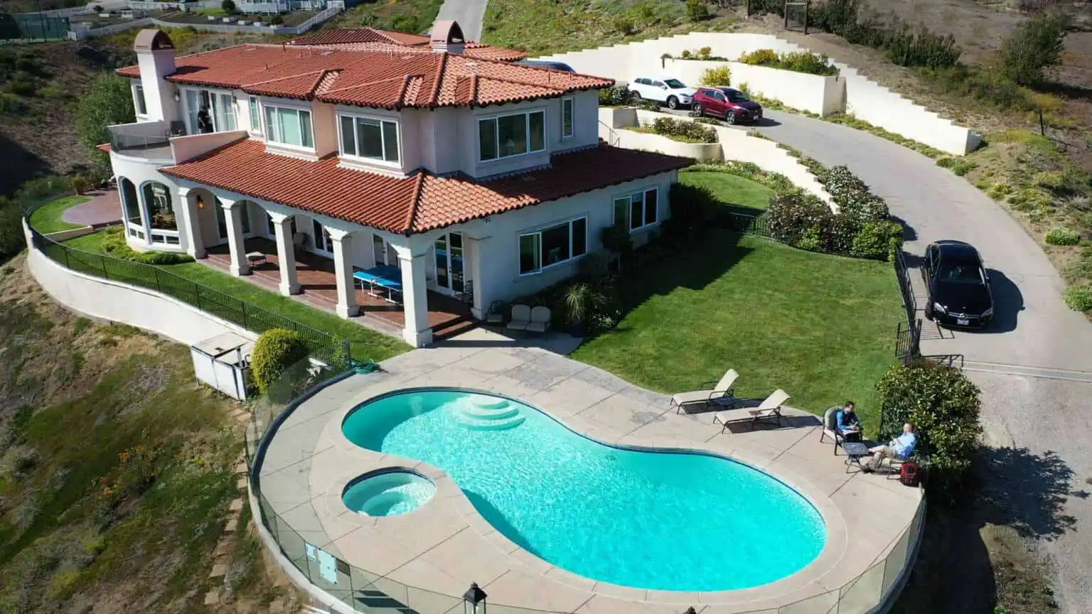 Aerial view of residence with curved pool and surrounding hills