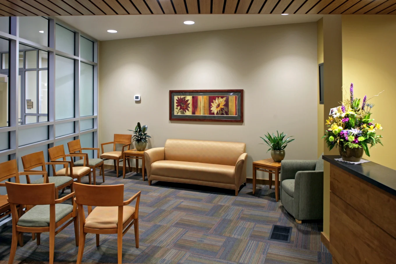 Waiting area with chairs, sofa, plants, and floral artwork