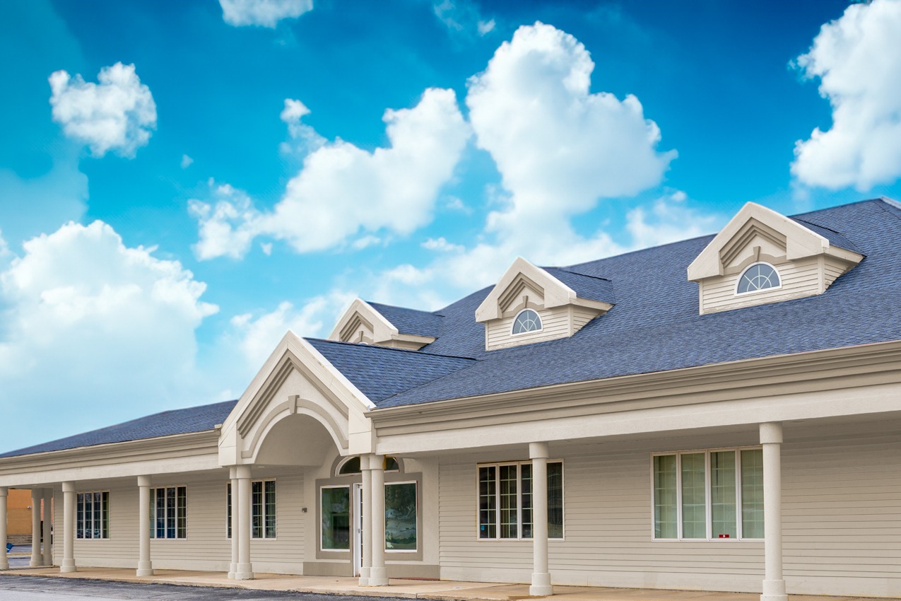 Rehab center exterior with dormer windows under blue sky.