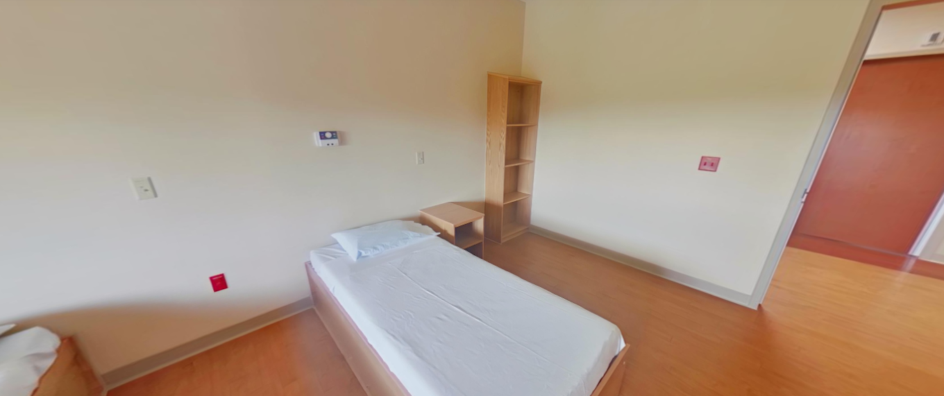 Simple inpatient bedroom with twin bed and shelving