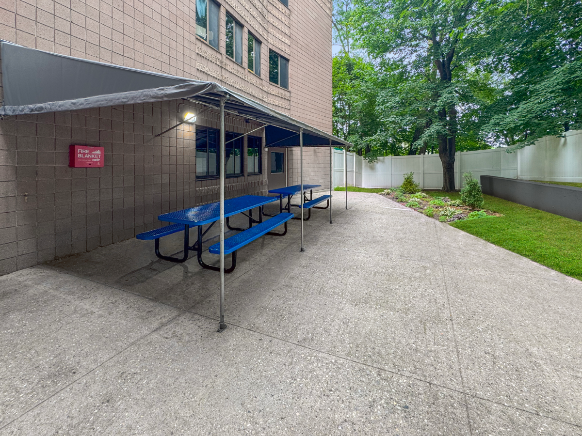 Covered outdoor seating with picnic tables alongside the facility at Boca Recovery Center Massachusetts