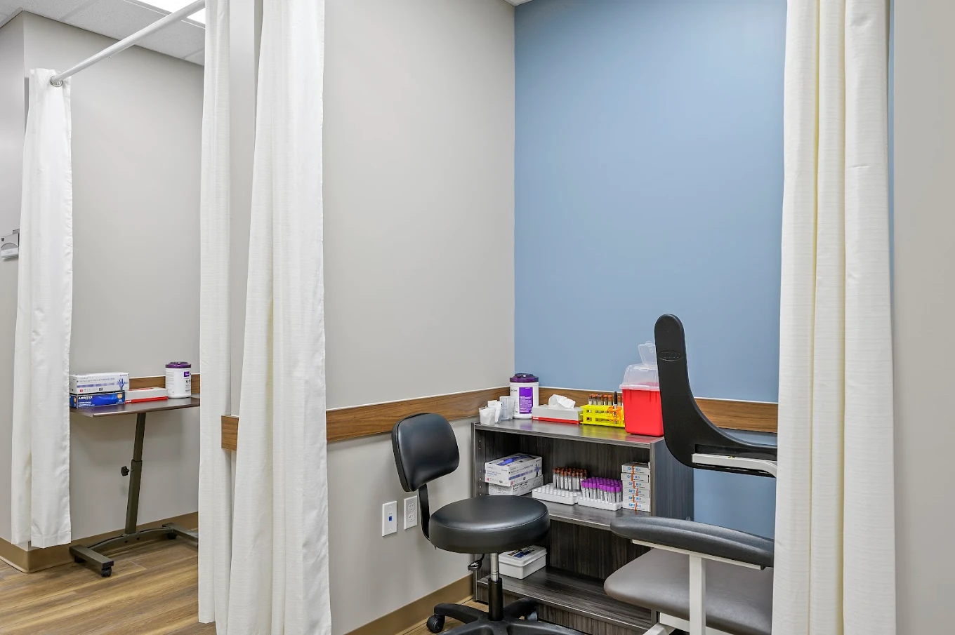 Clinical testing area with privacy curtains, patient chair, and specimen supplies