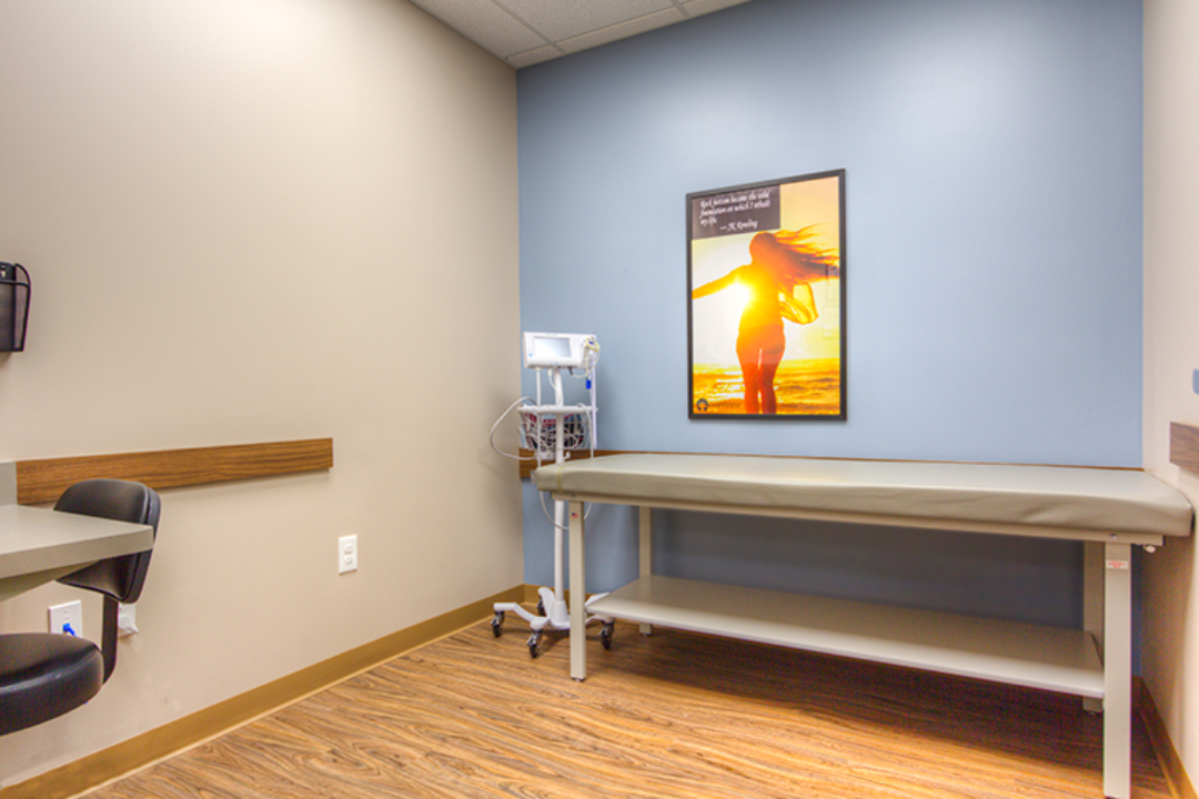 BrightView Ashtabula exam room with exam table, vital signs monitor, blue accent wall, and wood-look flooring