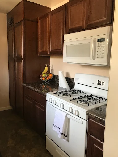 Kitchen with dark wood cabinets, white appliances, and granite counters.