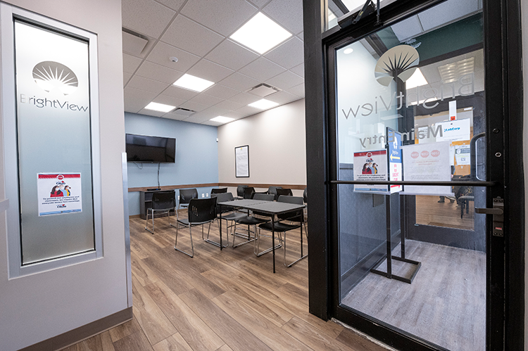 BrightView Health Zanesville lobby and group seating area with black chairs, tables, wall-mounted television, and wood-look flooring