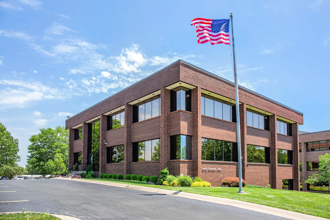Brick building exterior with American flag and parking area