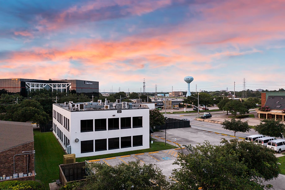 Side view of white rehab facility under a colorful sunset sky