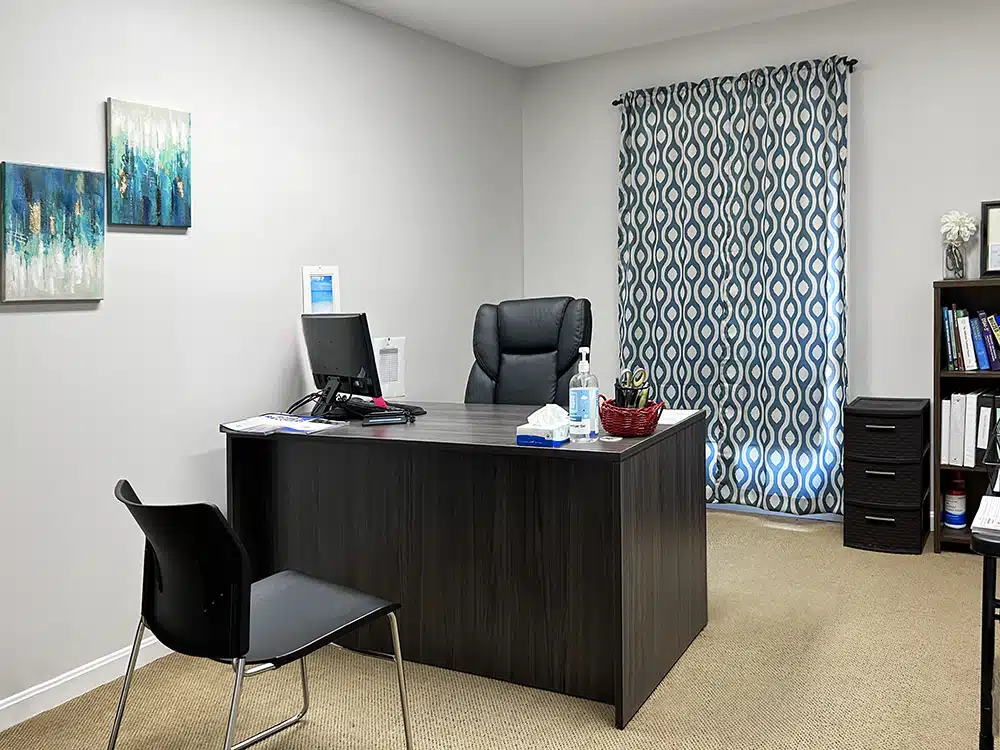 Private counseling office with desk, chair, and patterned curtains