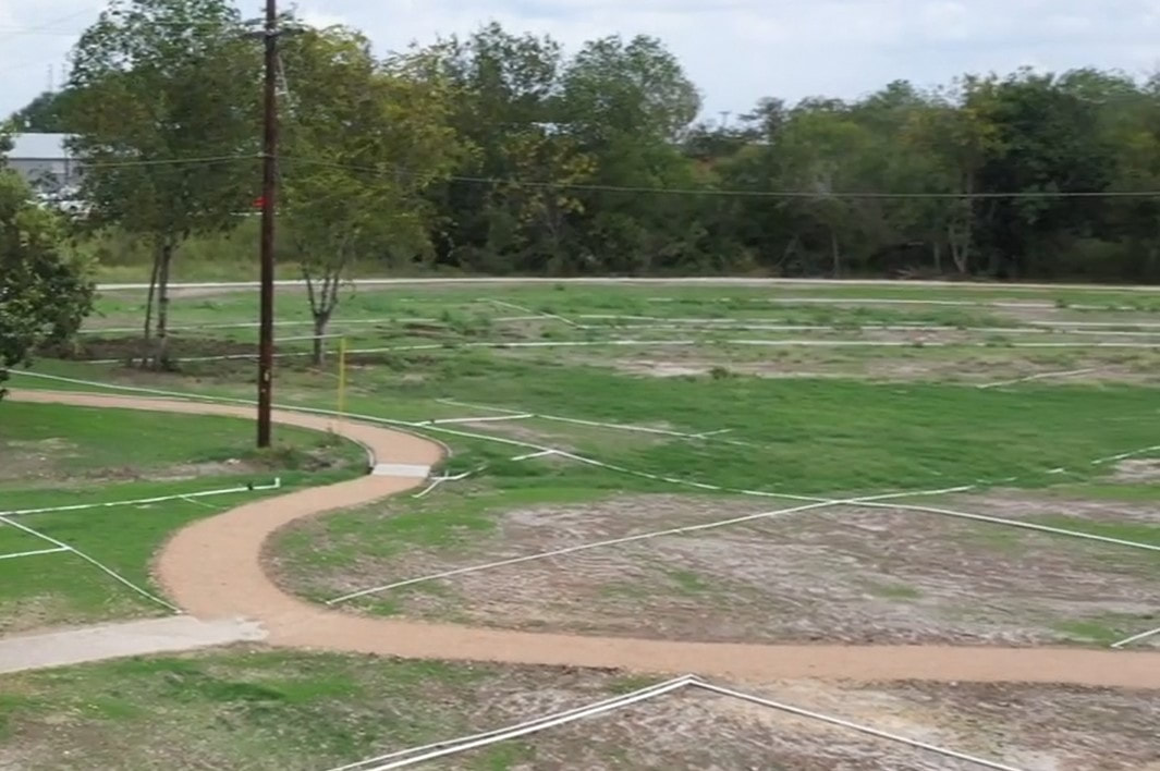 Curved walking trail through grassy open field