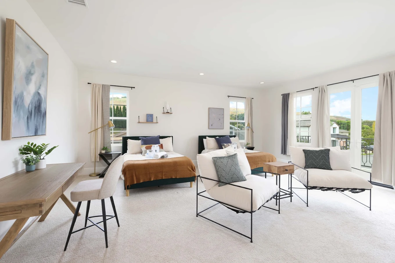 Bright bedroom with bed, sitting area, and large windows