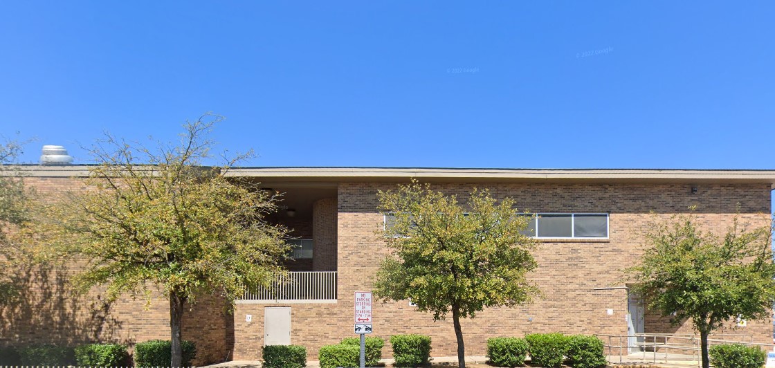 A large brick building with dark trim, surrounded by trees, serving as a detox facility.