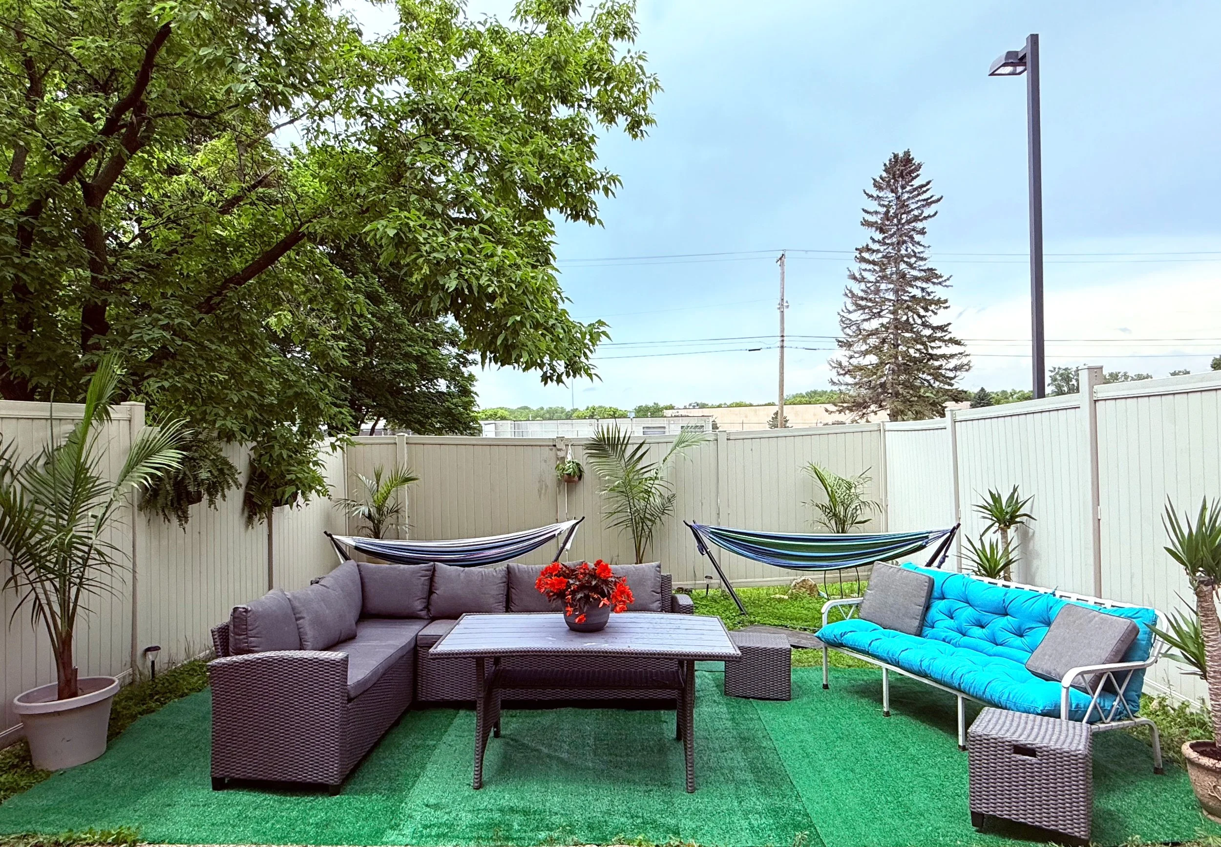 Outdoor lounge with seating, hammocks, and fenced green space